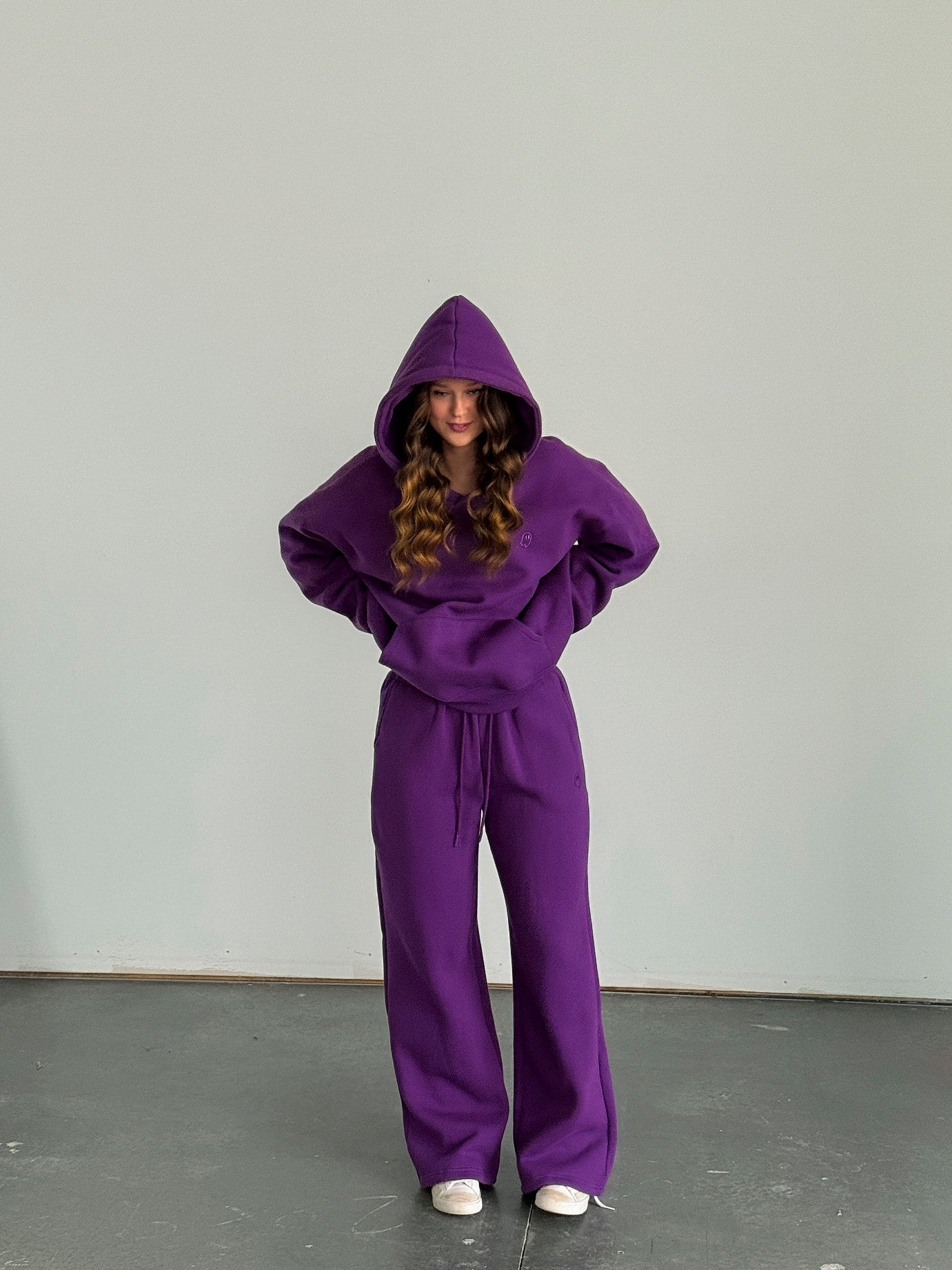 Person wearing a purple hoodie and pants set against a plain background