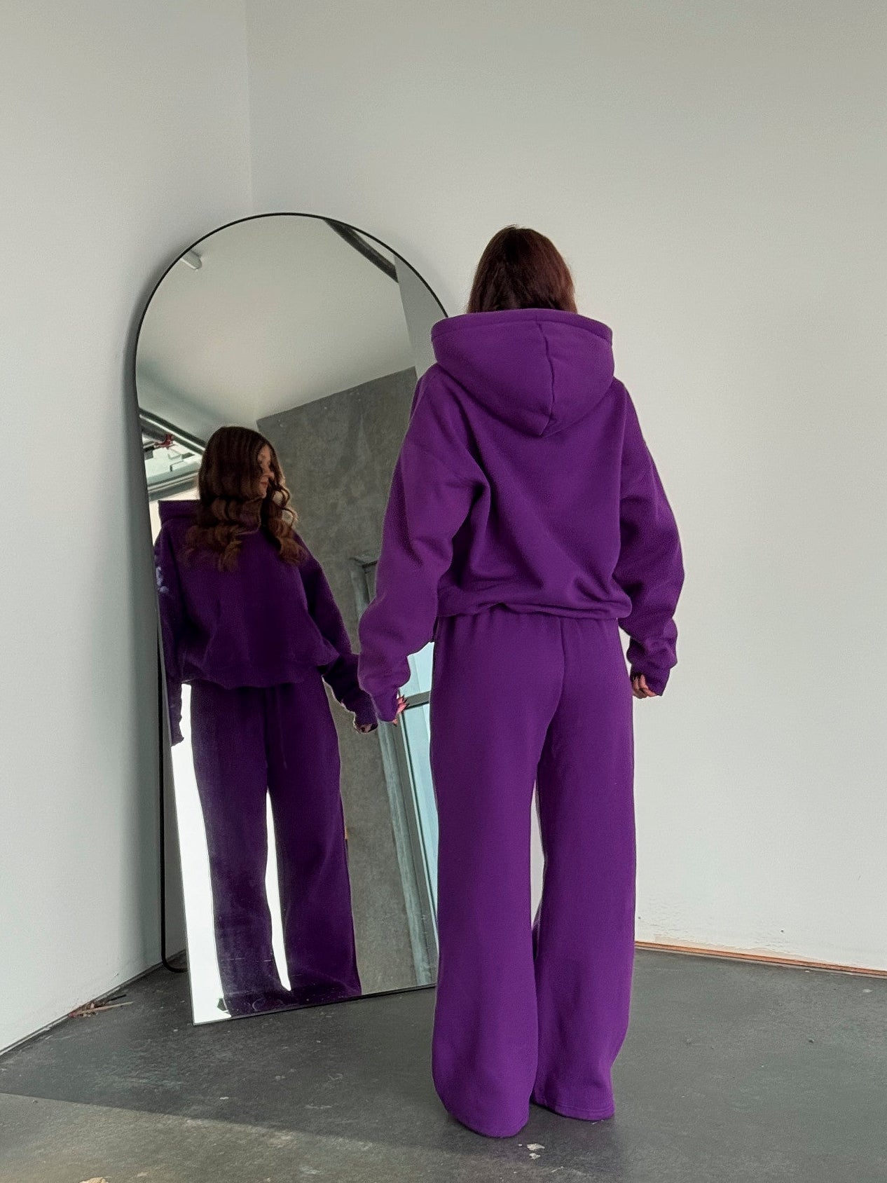 Person wearing a purple tracksuit standing in front of a mirror.