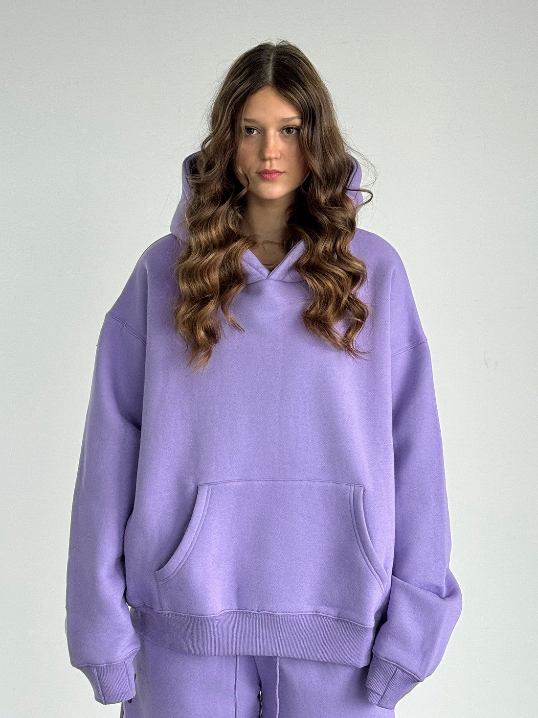 Person wearing a purple hoodie and pants on a plain background