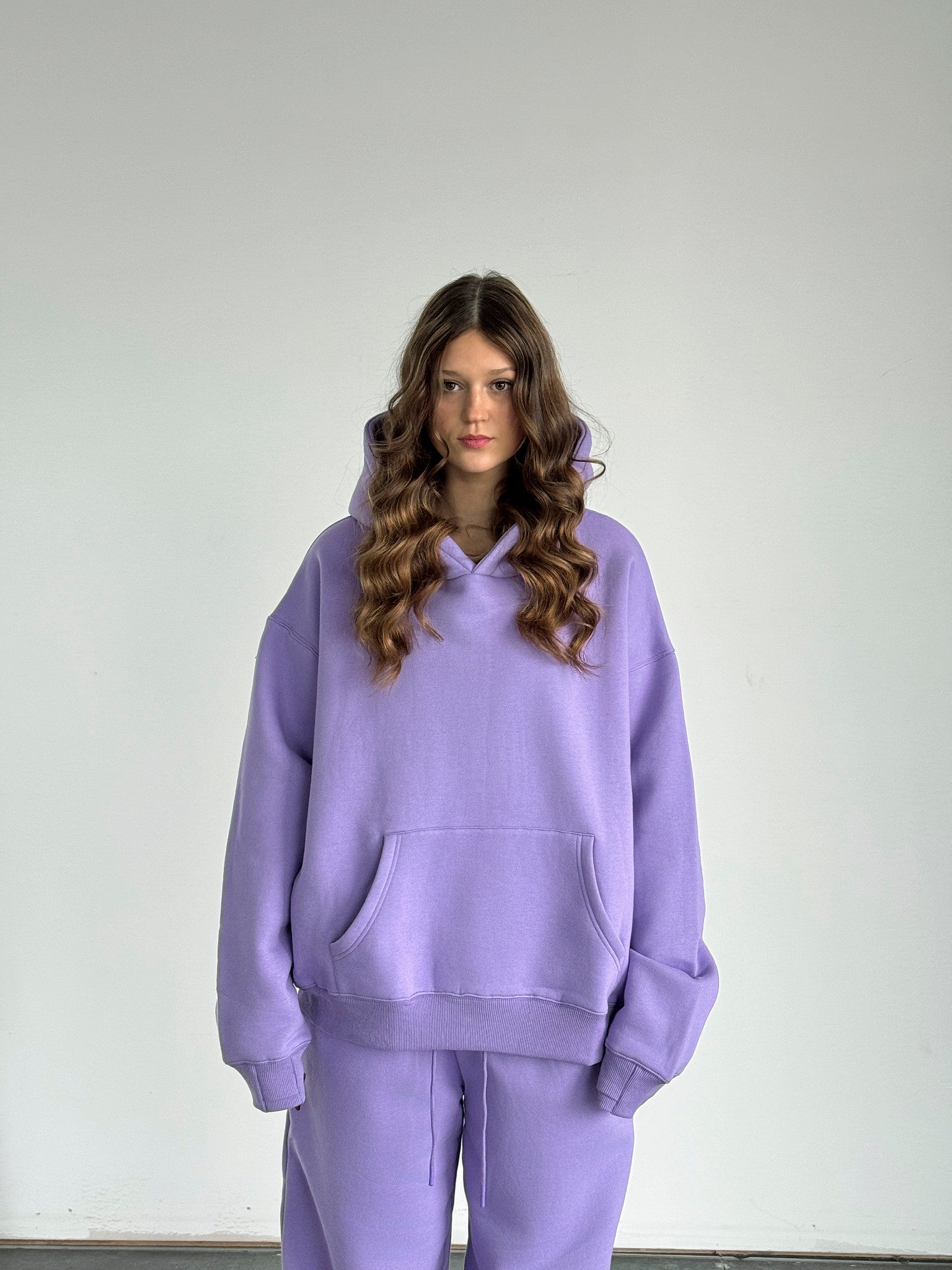 Person wearing a purple hoodie and pants on a plain background