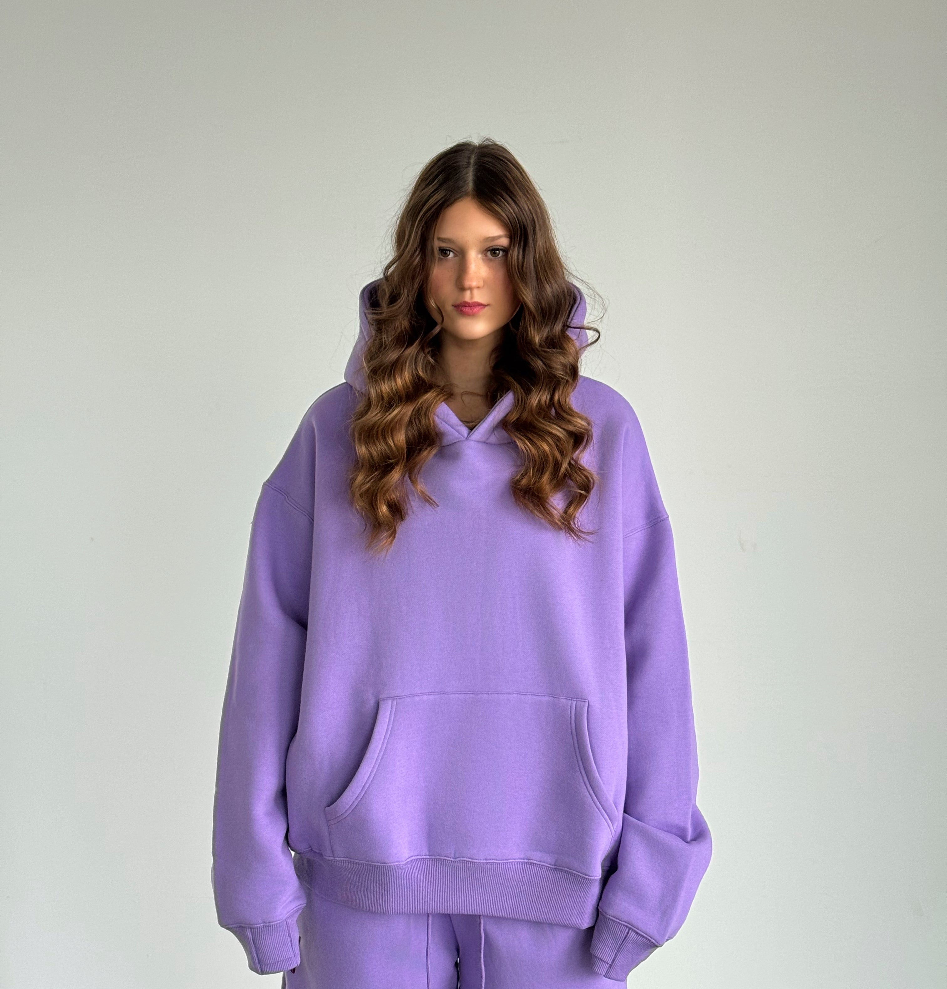 Person wearing a purple hoodie and pants against a plain background