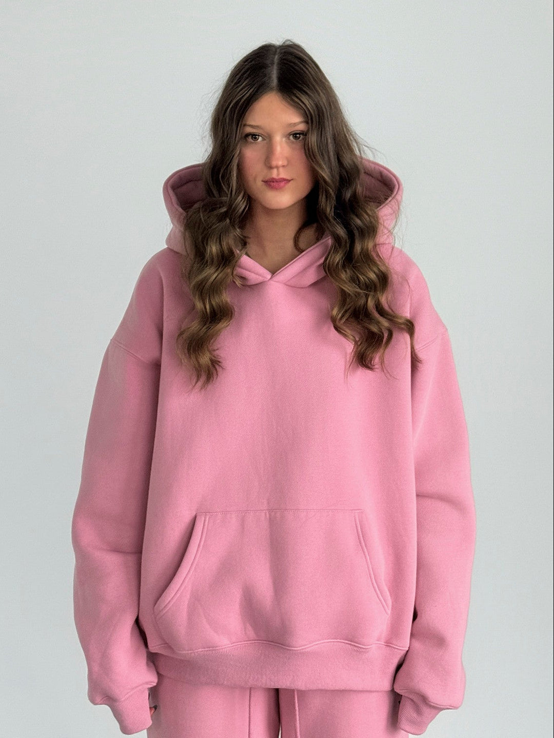 Person wearing a pink hoodie and pants set against a white background