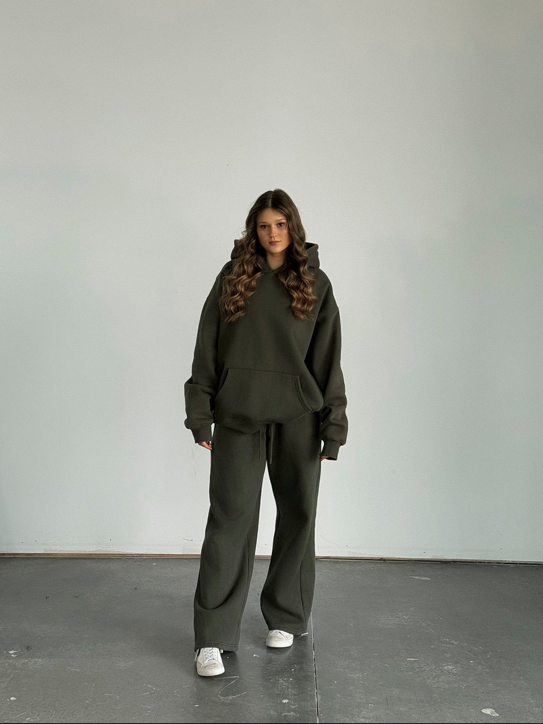 Person wearing a dark green tracksuit against a plain white background