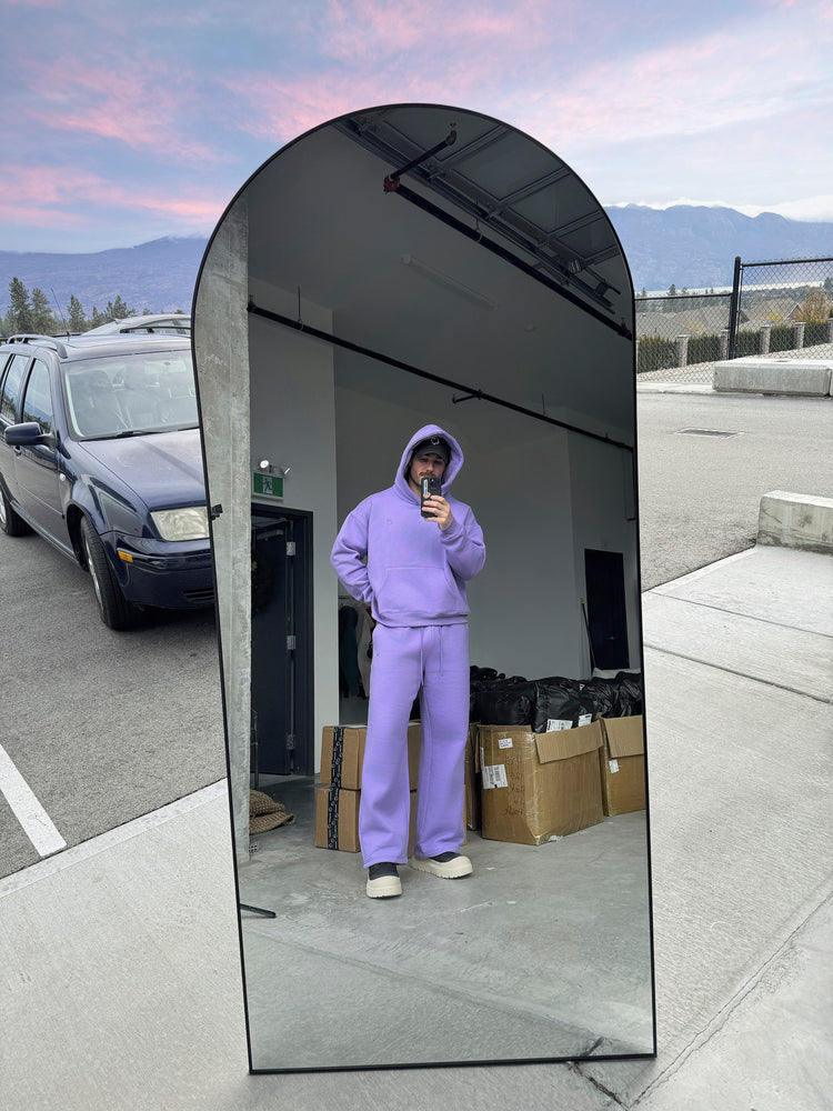 Person wearing a purple outfit taking a mirror selfie outdoors with mountains in the background.