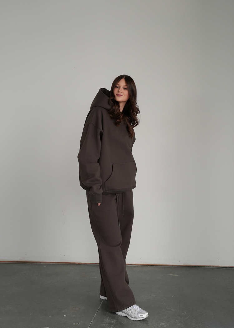 Person wearing a brown tracksuit standing against a plain background