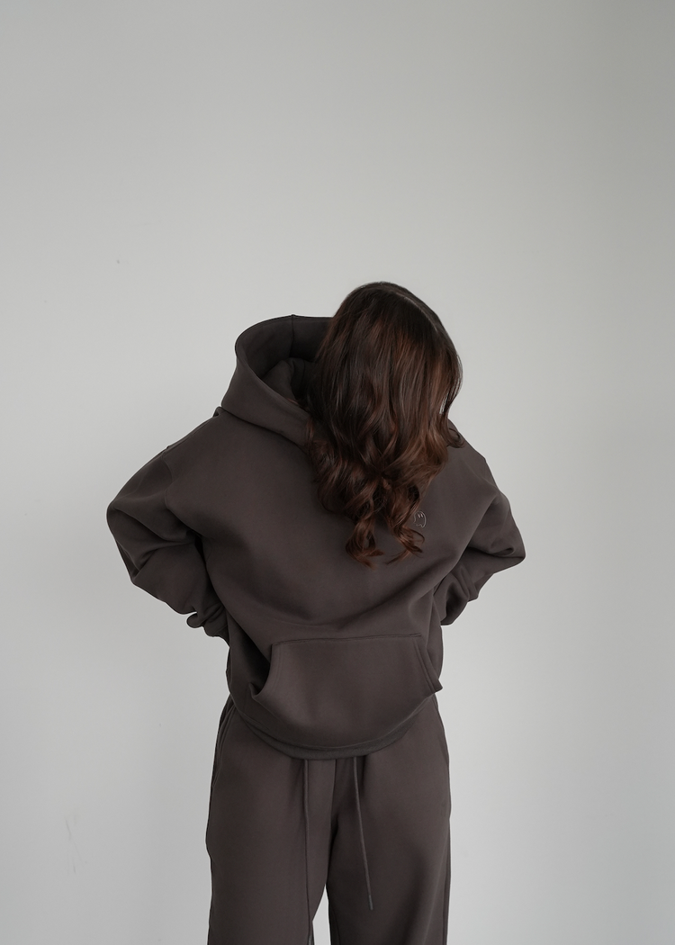 Person wearing a brown tracksuit against a plain white wall