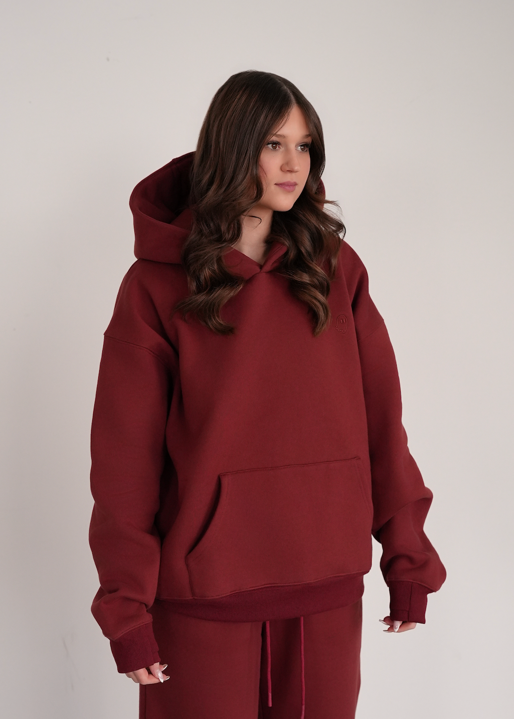 Person wearing a maroon hoodie and pants on a plain background