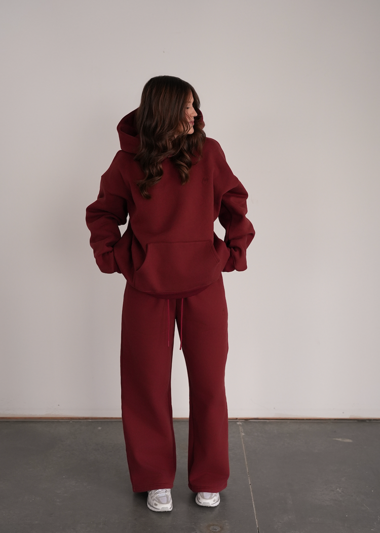 Person wearing a maroon tracksuit against a plain background