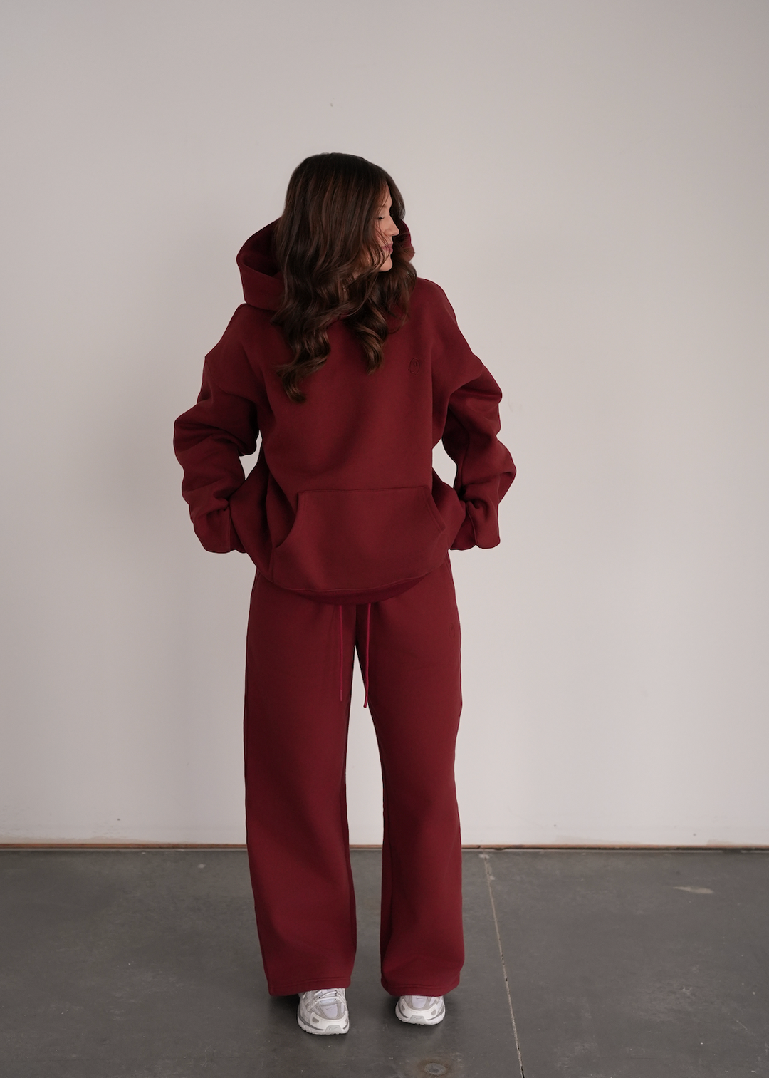 Person wearing a maroon tracksuit against a plain background