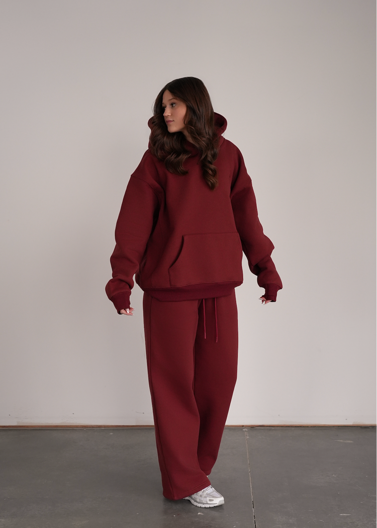 Person wearing a maroon tracksuit against a plain background