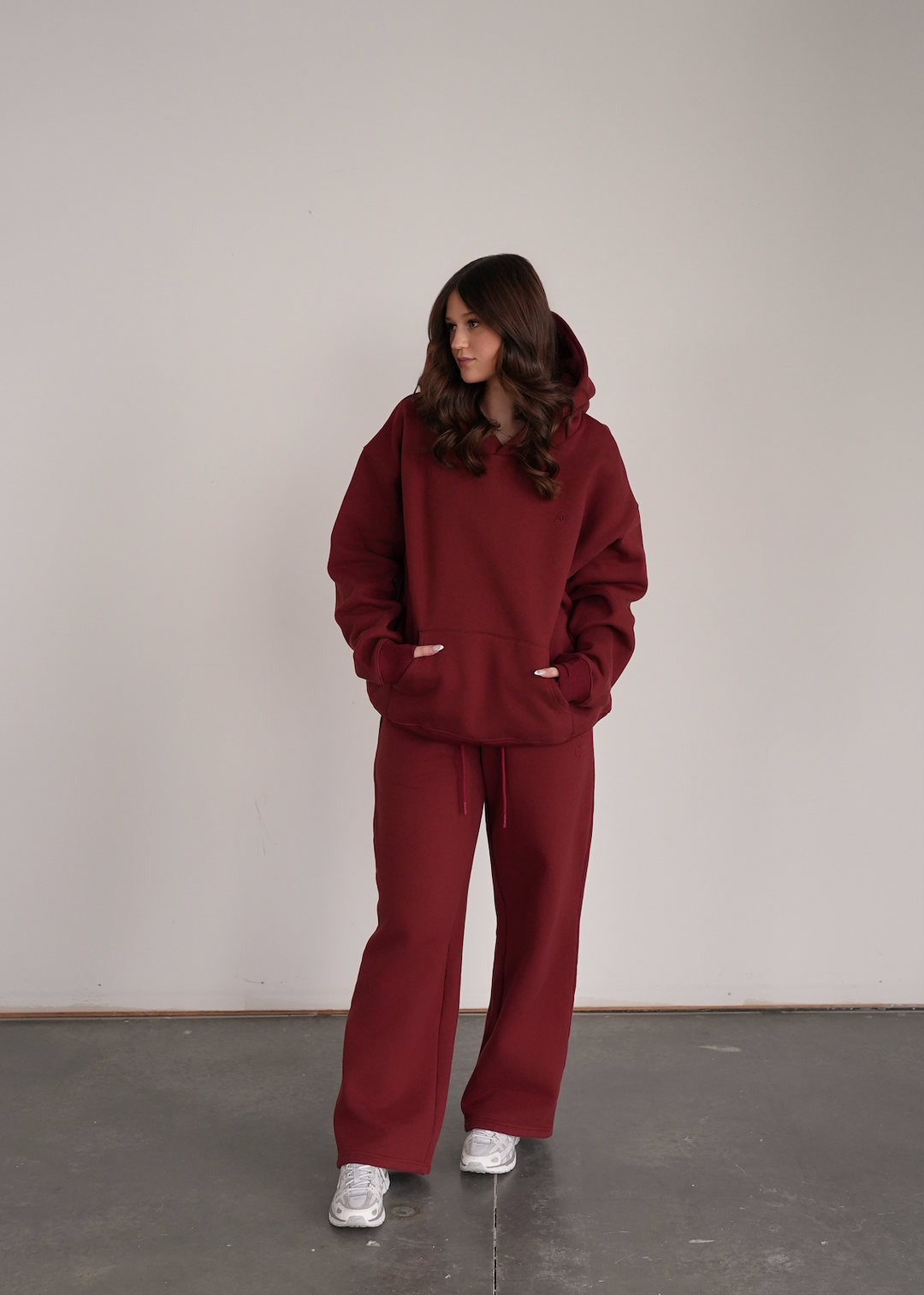 Person wearing a maroon hoodie and pants standing against a plain background