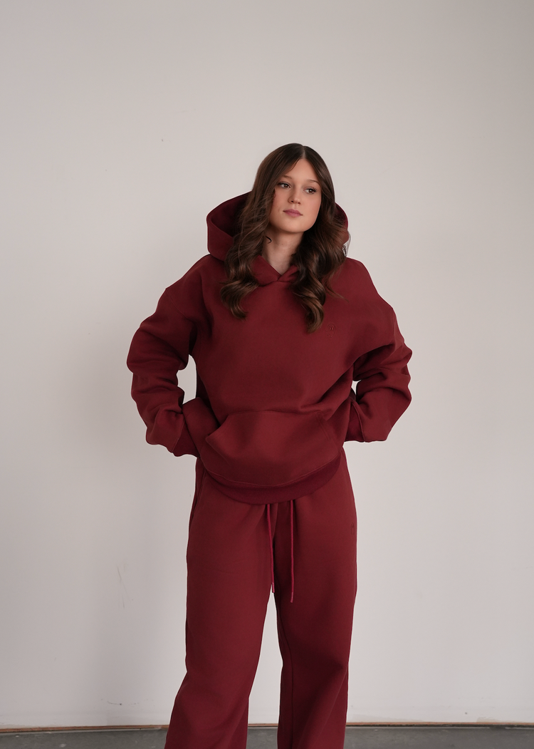 Person wearing a maroon tracksuit against a plain background