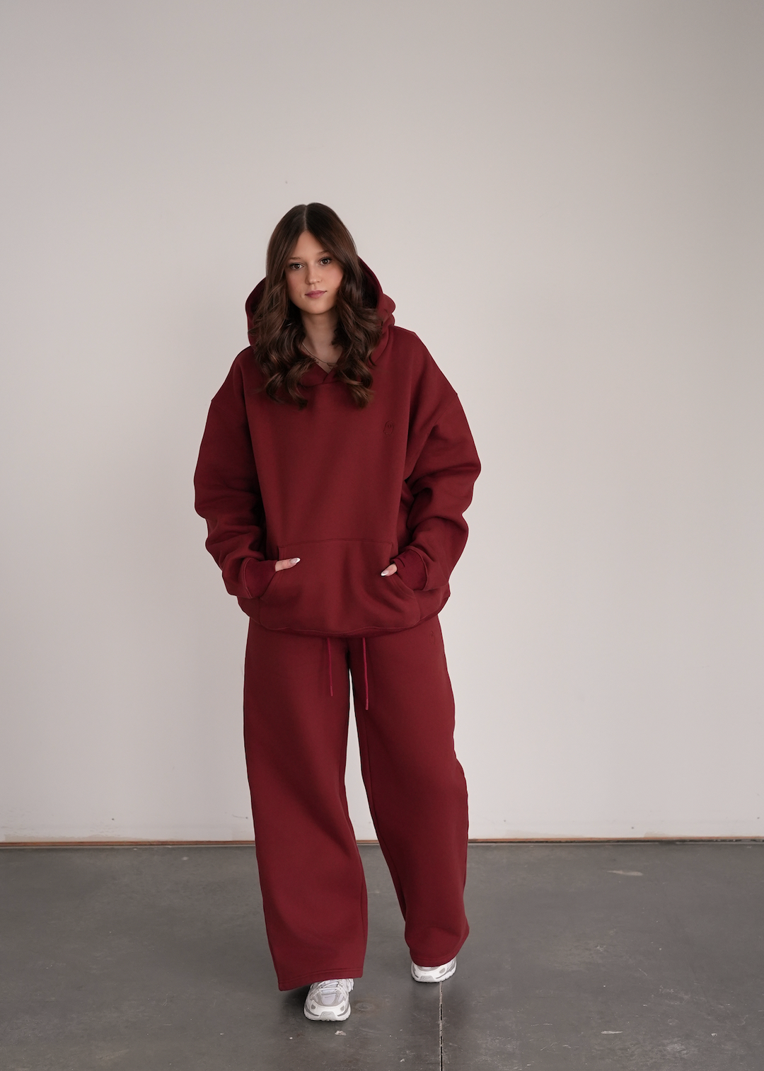 Person wearing a maroon hoodie and pants against a plain background