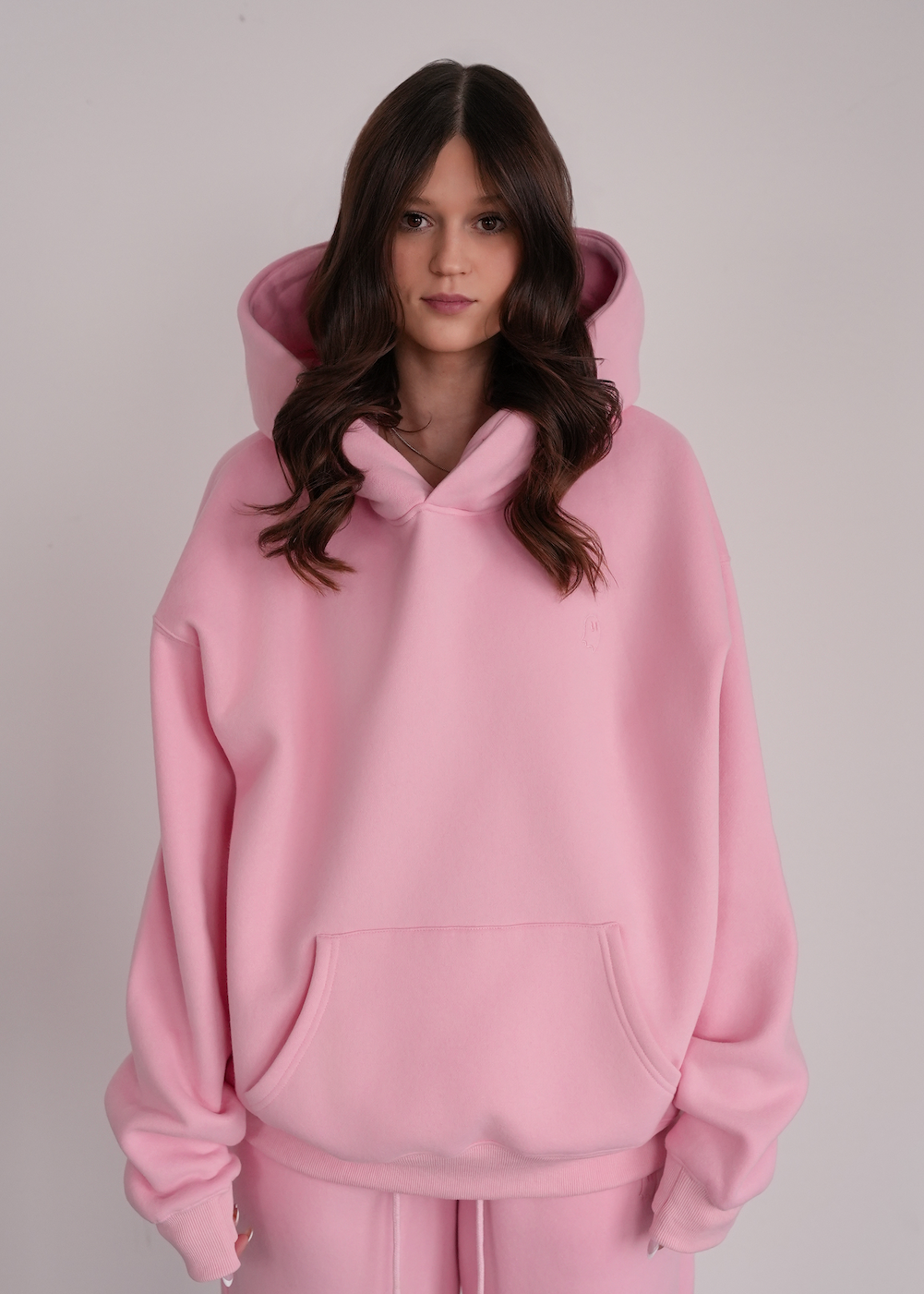 Person wearing a pink hoodie and pants on a plain background