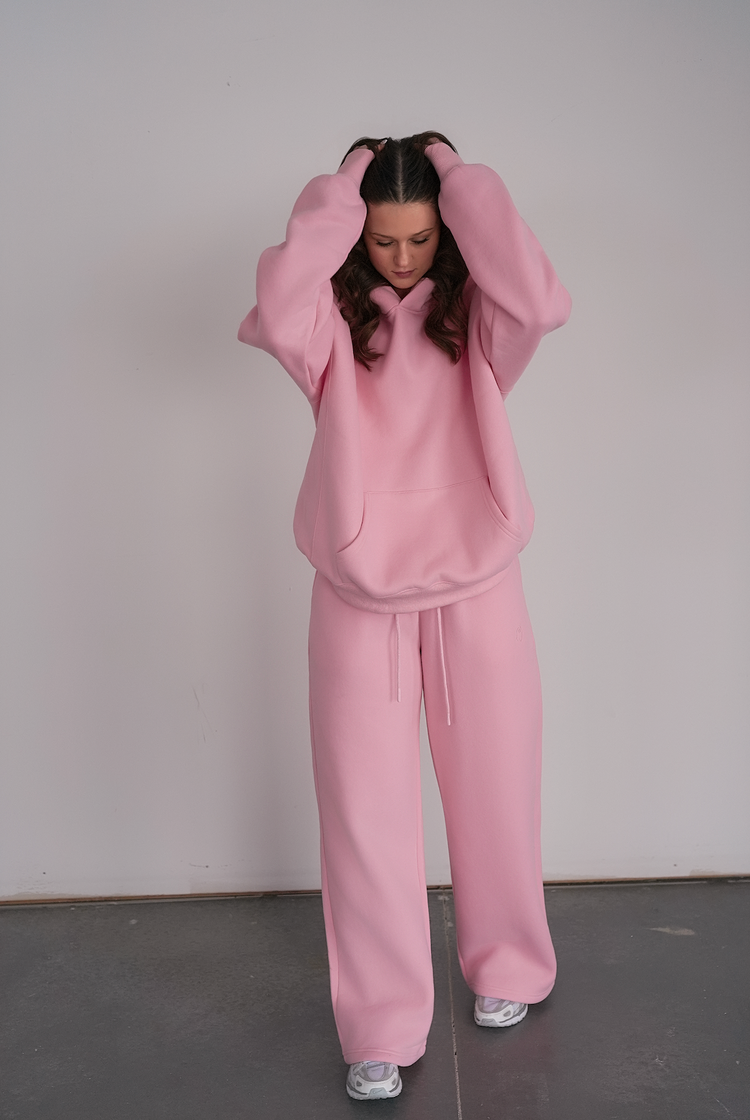 Person wearing a pink tracksuit against a plain background