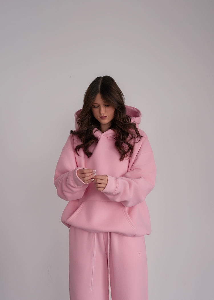 Person wearing a pink hoodie and pants on a plain background