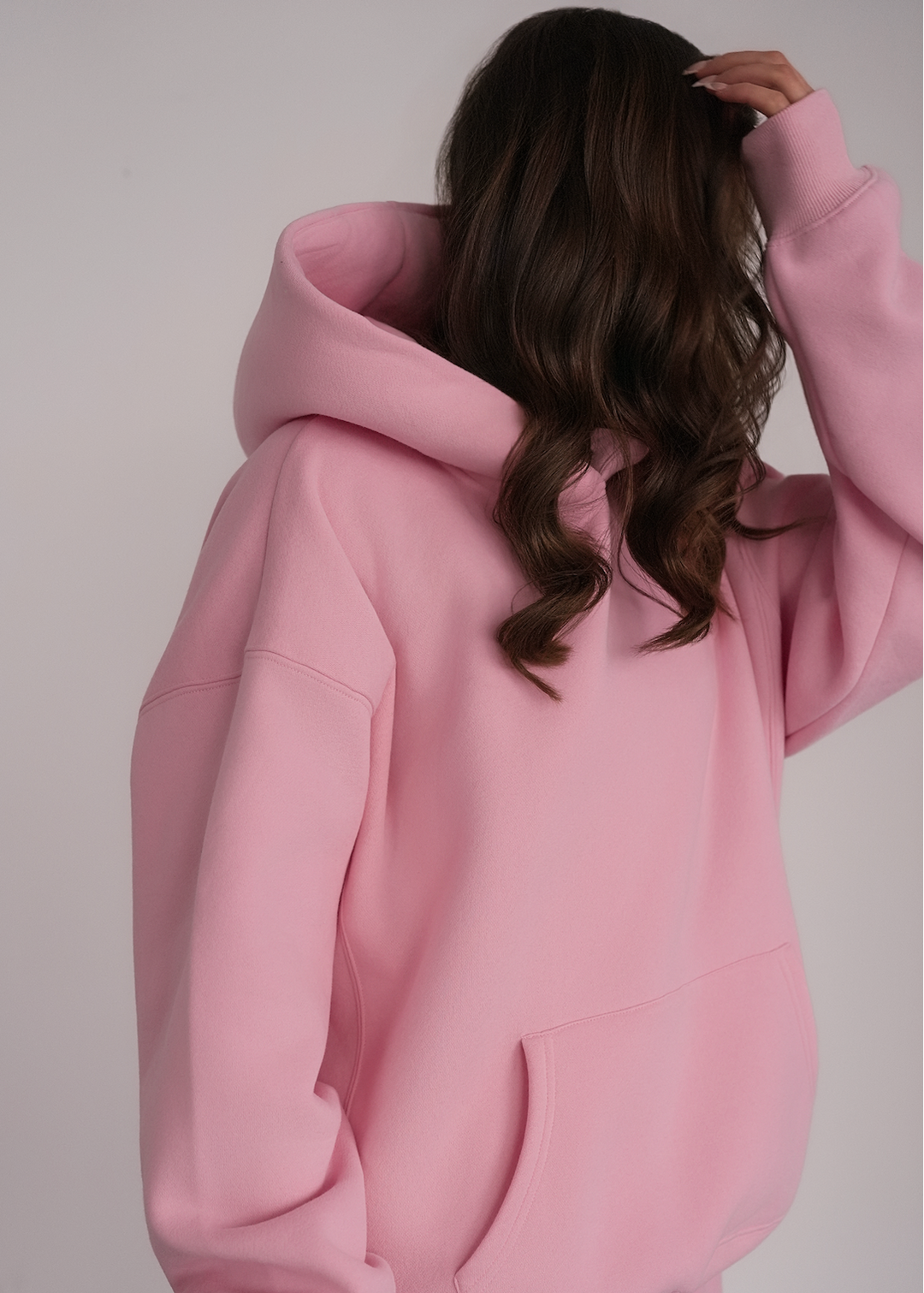 Person wearing a pink hoodie against a plain background