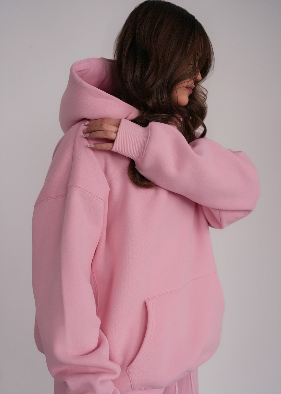 Person wearing a pink hoodie against a plain background