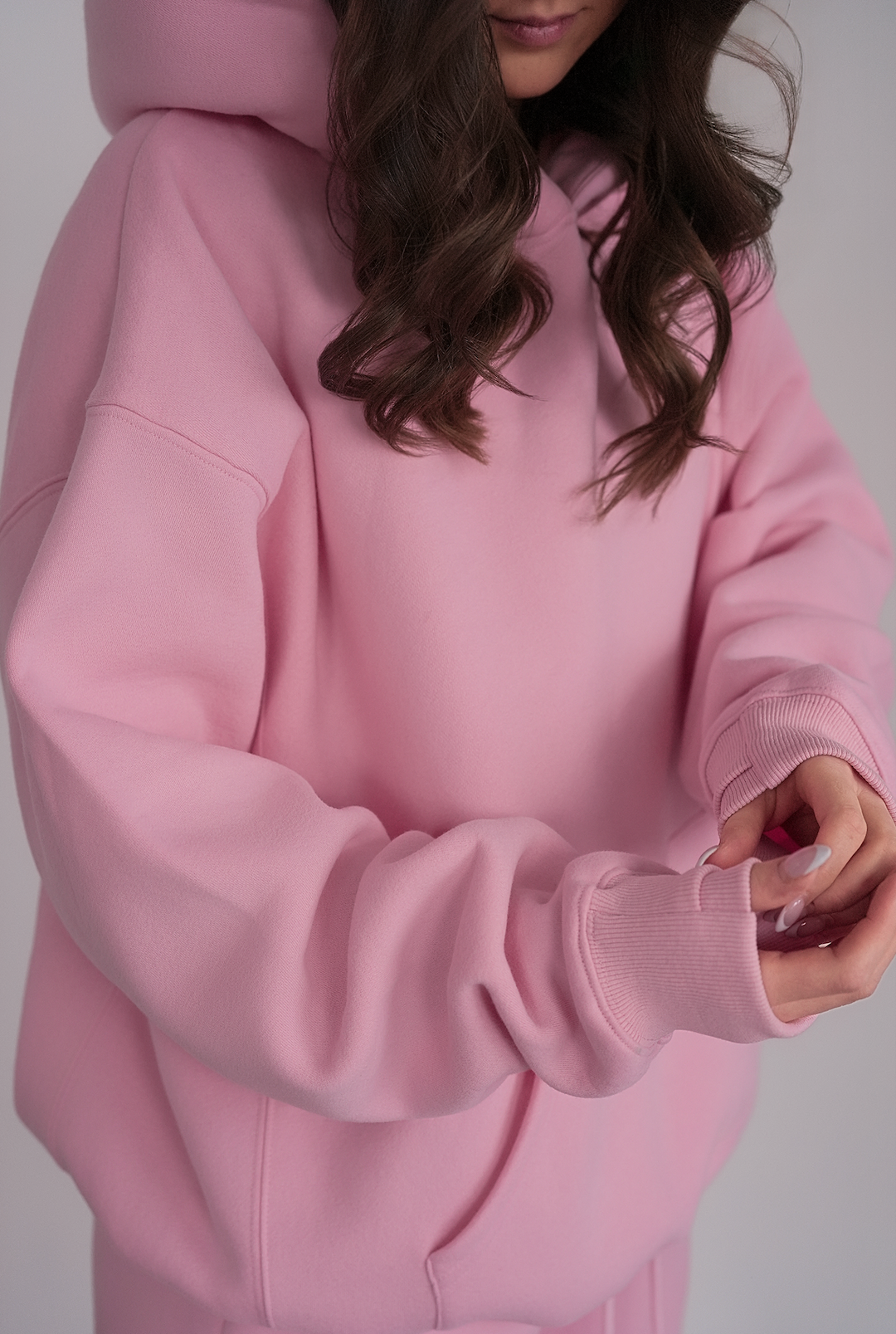 Person wearing a pink hoodie with a neutral background