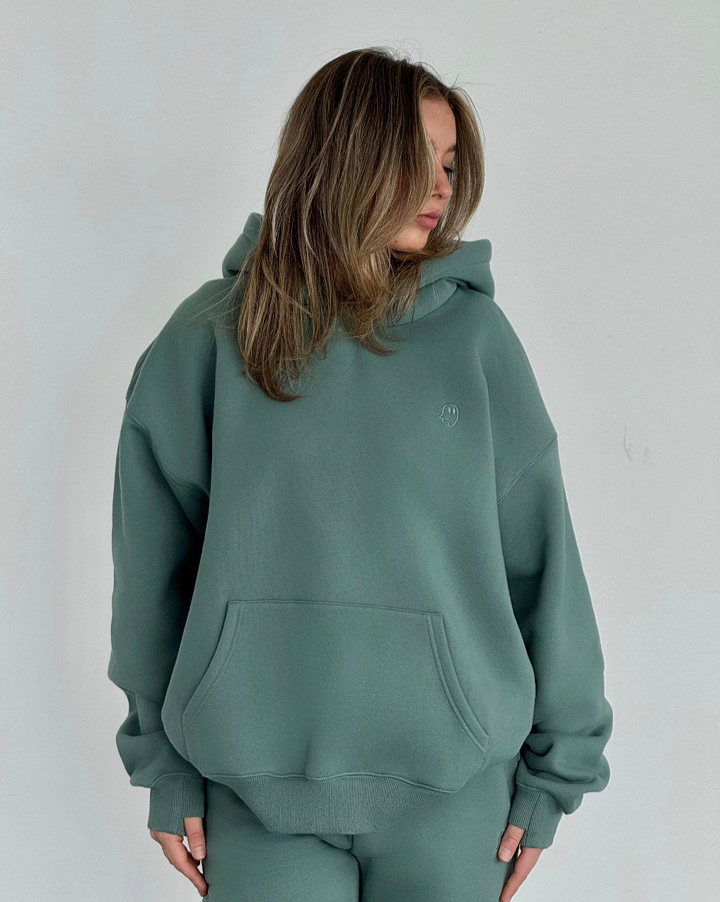Person wearing a green hoodie on a plain background