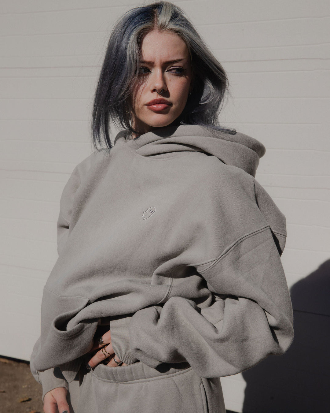 Person wearing a light gray hoodie against a plain background