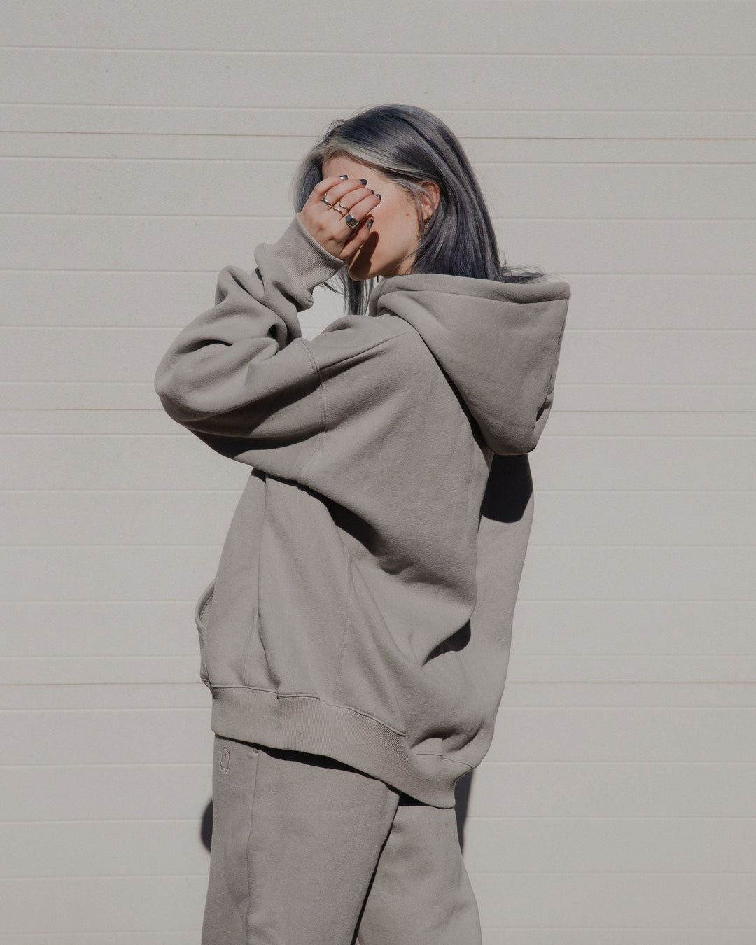 Person wearing a gray hoodie and pants against a plain background