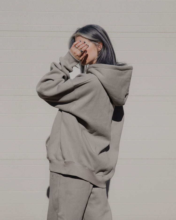 Person wearing a gray hoodie and pants against a plain background
