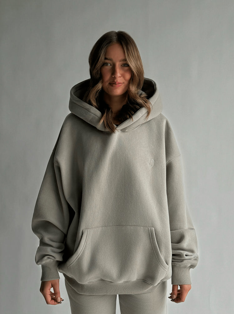 Person wearing a light gray hoodie on a plain background