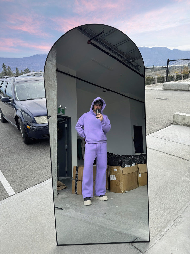 Person wearing a purple outfit taking a mirror selfie outdoors with mountains in the background.