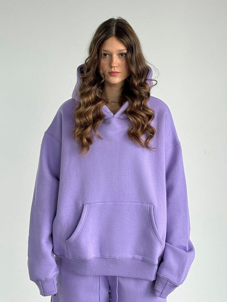 Person wearing a purple hoodie and pants on a plain background