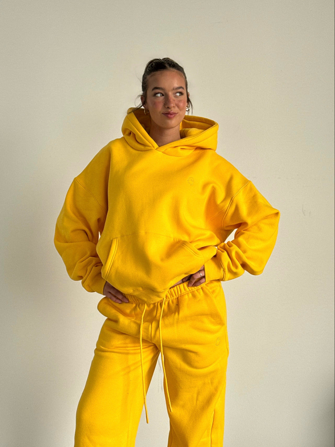 Person wearing a bright yellow hoodie and pants against a plain background